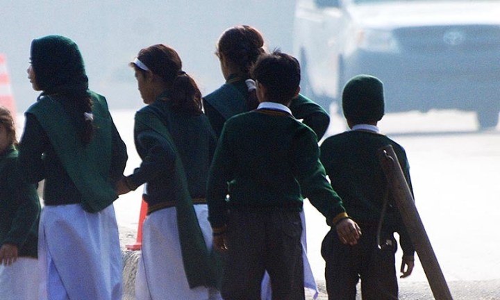 Schoolchildren cross a road as they move away from a military run school that is under attack by Taliban gunmen in Peshawar